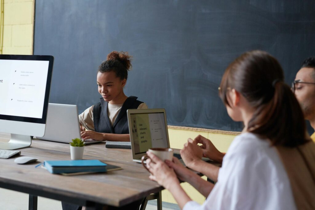 Two children using laptops at a table in a study environment.