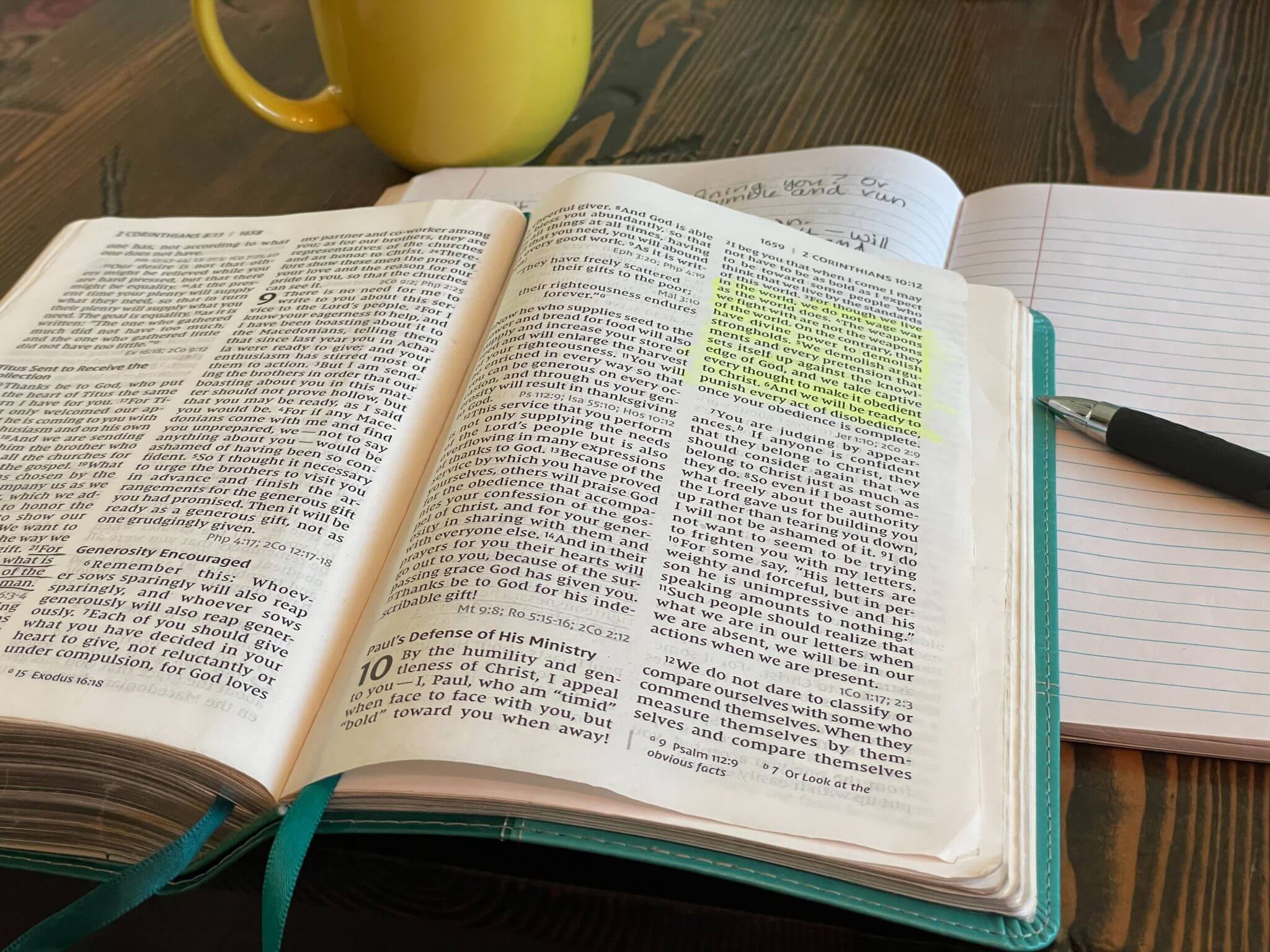 Open book with highlighted text and a yellow mug on the table.
