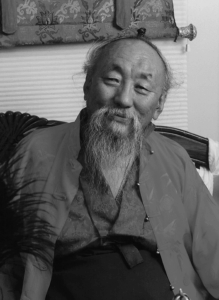 Elderly man with long beard smiling gently at the camera.