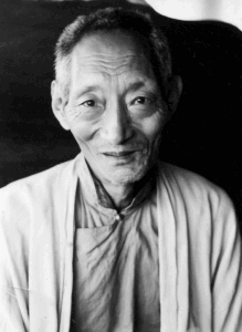 Portrait of a smiling elderly Asian man in traditional clothing.