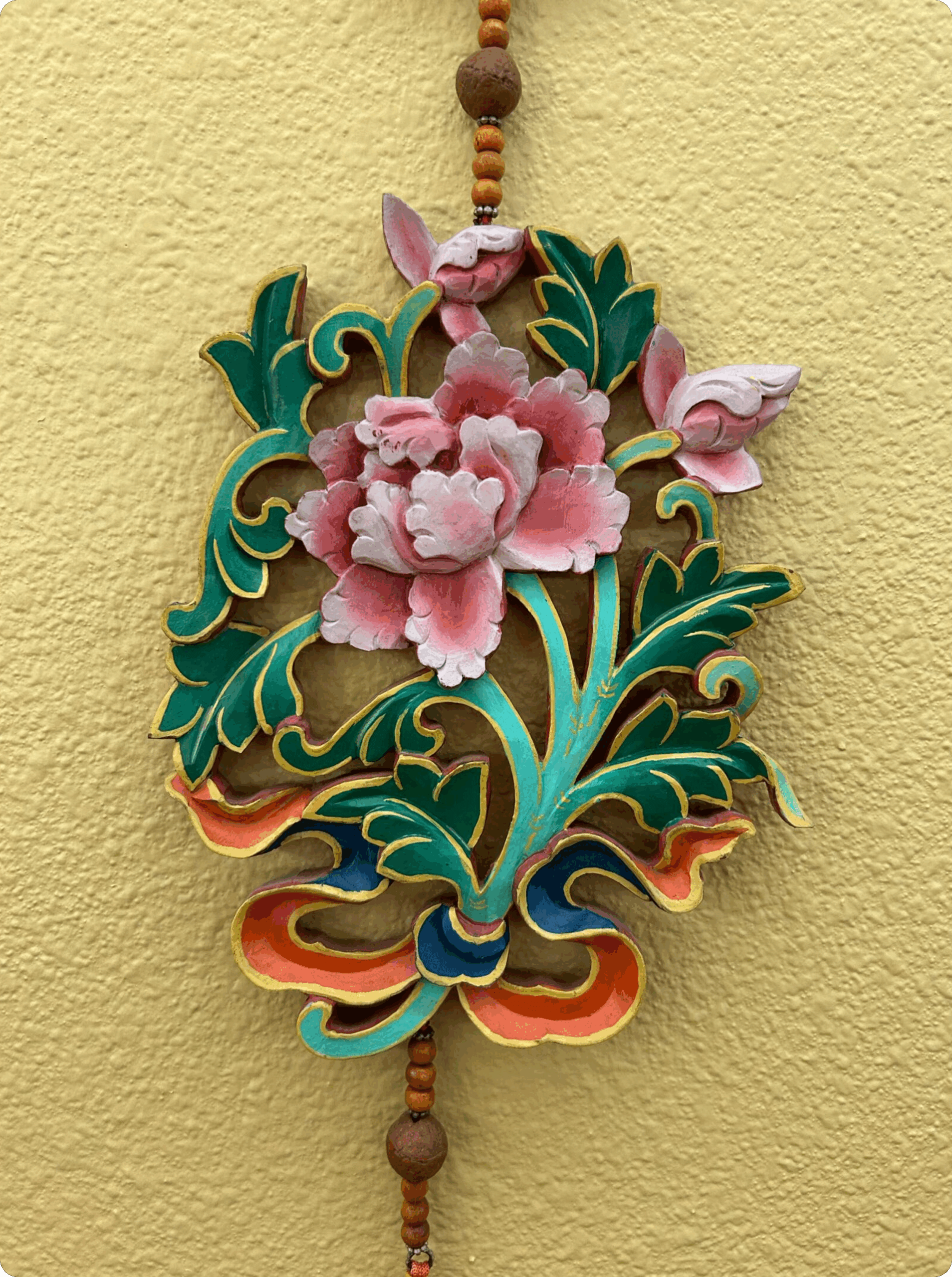Intricate floral embroidery with pink flowers and green leaves on fabric.